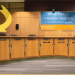 The school board dais with arrow pointing to one seat and text 
